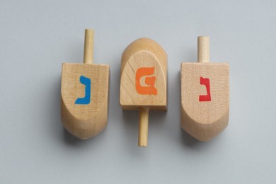 Photo of Wooden dreidels on grey background, flat lay. Traditional Hanukkah game