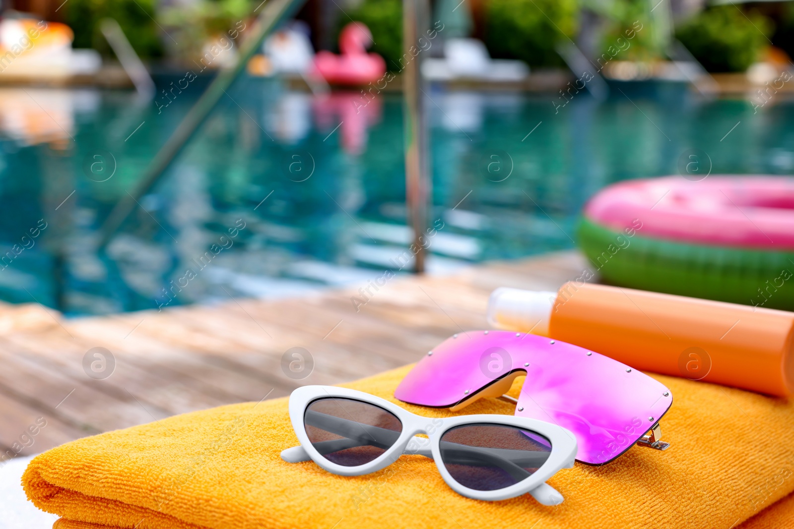 Photo of Beach towels and sunglasses near outdoor swimming pool at luxury resort, closeup. Space for text