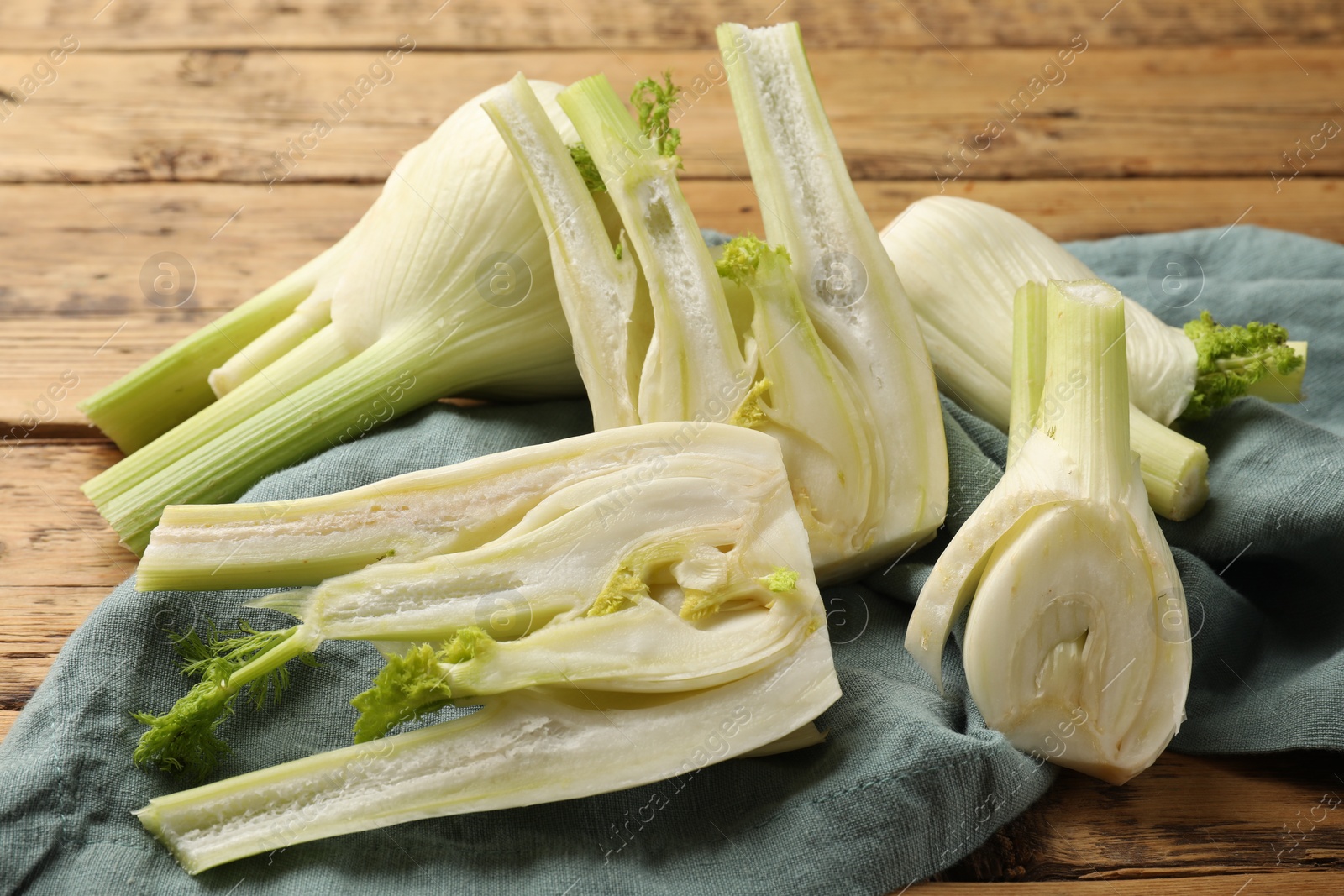 Photo of Whole and cut fennel bulbs on table, closeup