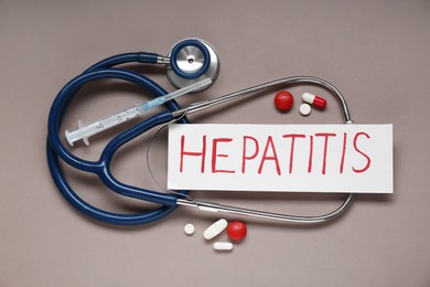 Photo of Word Hepatitis, stethoscope, syringe and pills on beige background, flat lay
