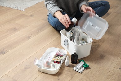 Woman putting medicament into first aid kit indoors, closeup. Space for text