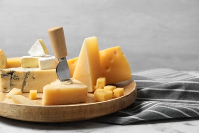 Different types of delicious cheese in plate on marble table against light background, space for text