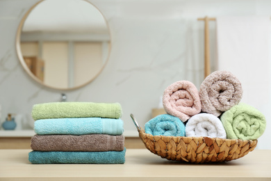 Fresh color towels on wooden table in bathroom