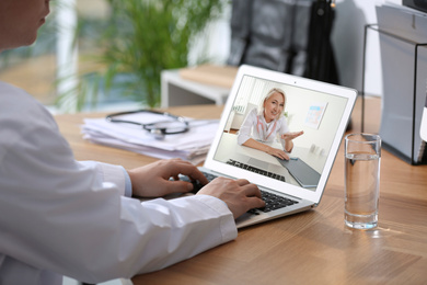 Image of Woman using laptop for online consultation with mature female doctor, closeup 