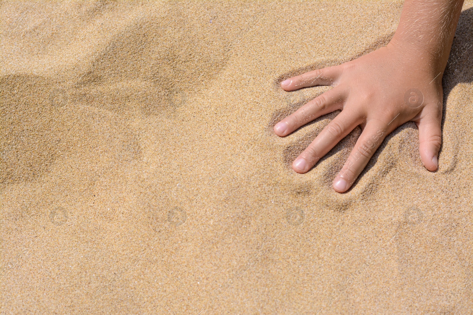 Photo of Child leaving handprint on sand outdoors, closeup with space for text. Fleeting time concept