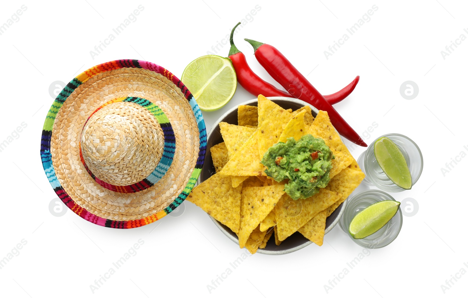 Photo of Mexican sombrero hat, tequila with lime, chili peppers, nachos chips and guacamole in bowl isolated on white, top view