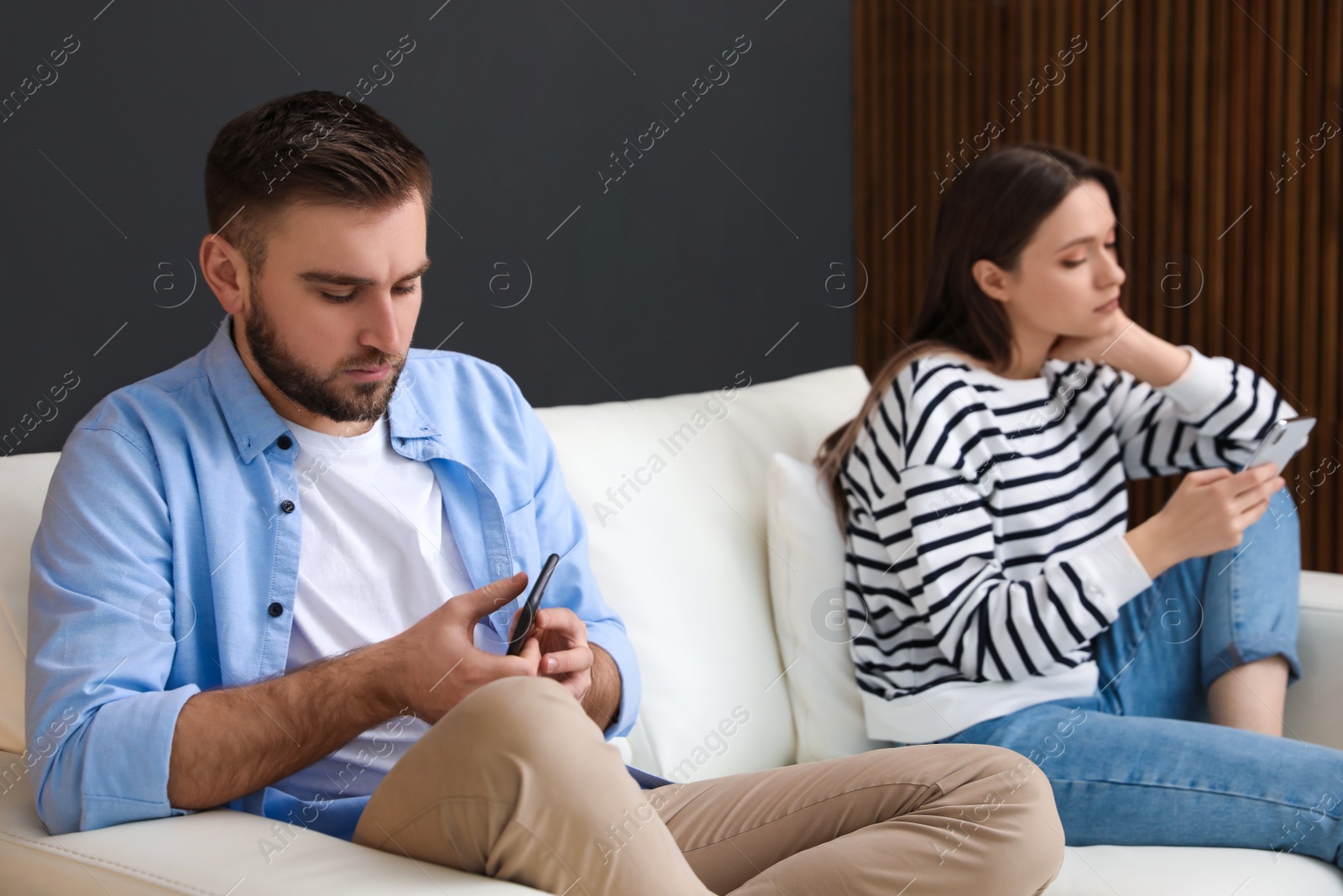 Photo of Couple addicted to smartphones ignoring each other at home. Relationship problems