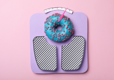 Photo of Scales made with donut on pink background, top view