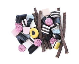 Photo of Many tasty candies and dried sticks of liquorice root isolated on white, top view