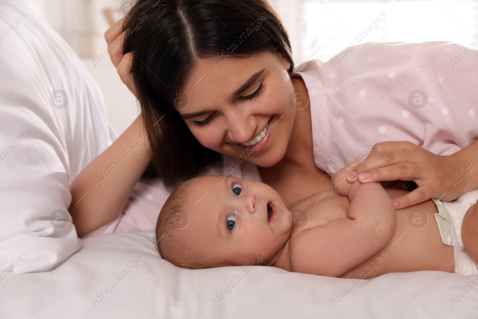 Photo of Happy young mother with her cute baby on bed at home