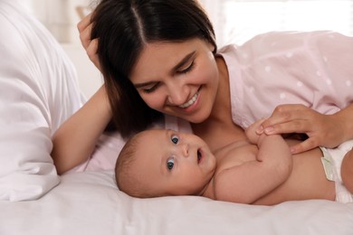 Happy young mother with her cute baby on bed at home