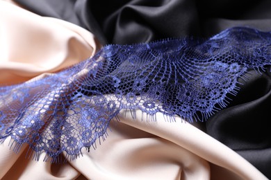 Photo of Beautiful blue lace on color fabrics, closeup