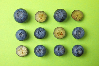 Photo of Tasty ripe blueberries on green background, flat lay