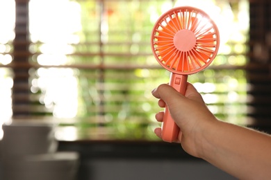 Closeup view of little child with portable fan at home, space for text. Summer heat