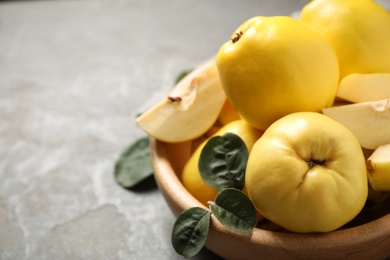 Photo of Fresh ripe organic quinces with leaves in bowl, closeup. Space for text