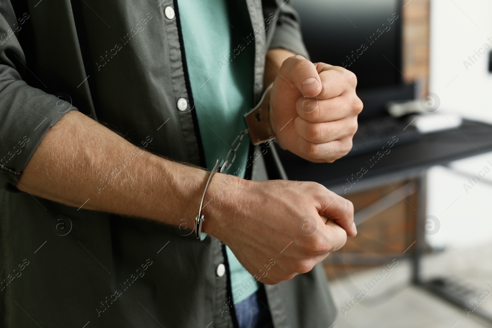 Photo of Man detained in handcuffs indoors, closeup view. Criminal law