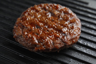 Photo of Prepared meat cutlet for burger on grill, closeup