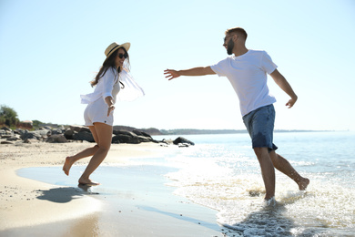 Photo of Happy young couple having fun on beach near sea. Honeymoon trip