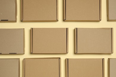 Photo of Many closed cardboard boxes on pale yellow background, flat lay