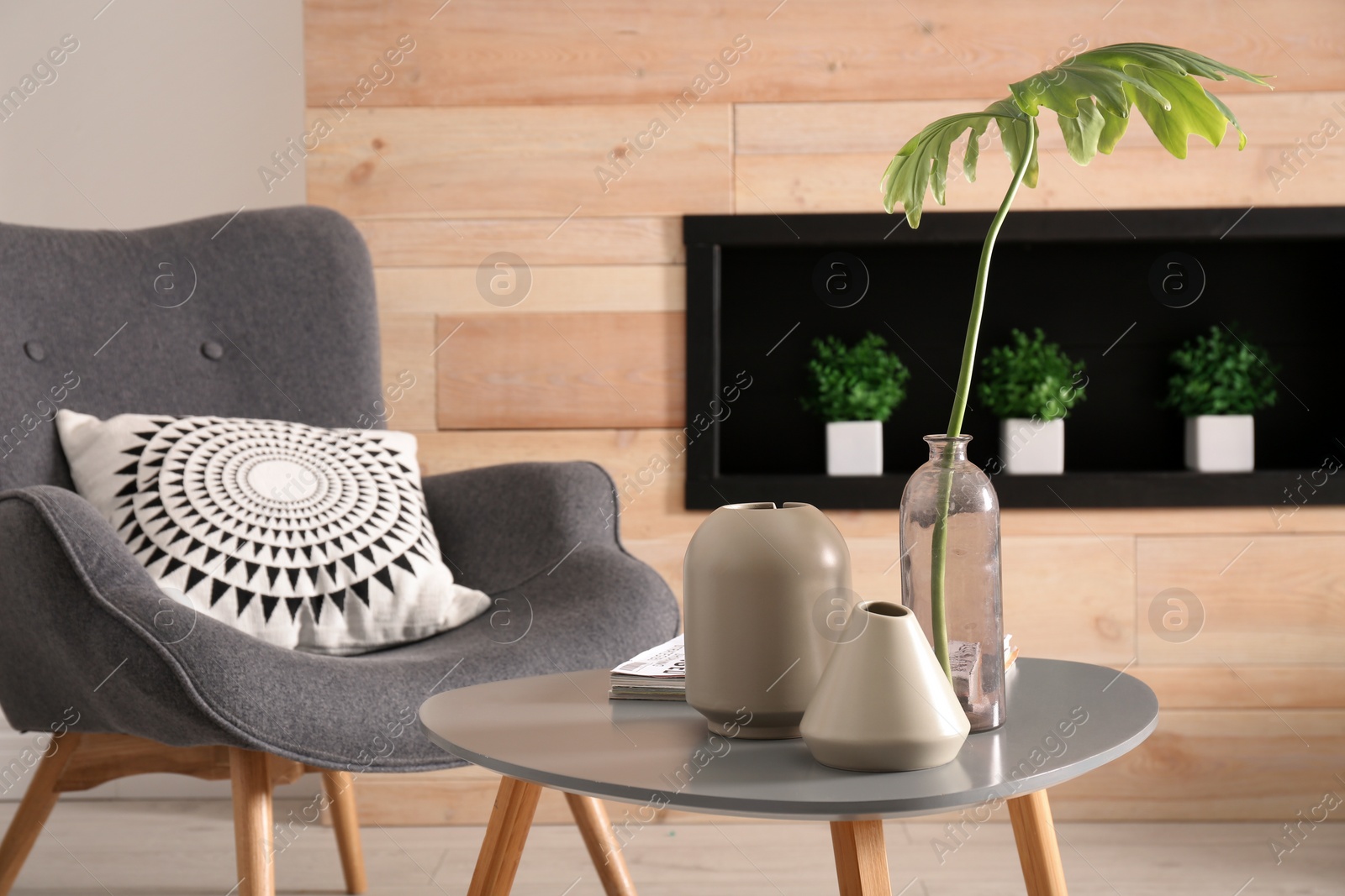 Photo of Living room interior with vases on table and armchair near wooden wall