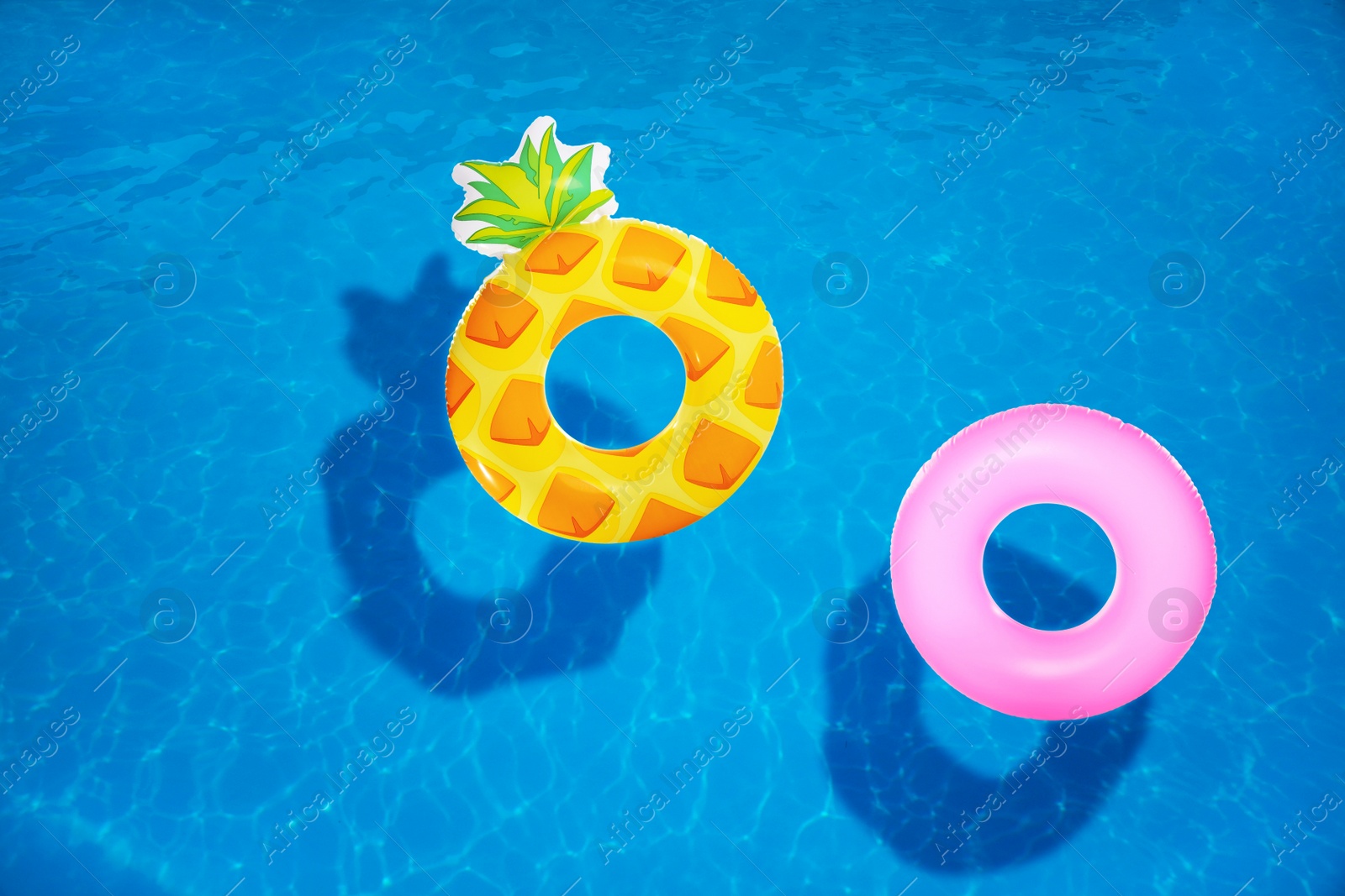 Image of Different inflatable rings floating in swimming pool, top view