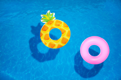 Image of Different inflatable rings floating in swimming pool, top view