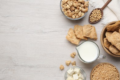 Different natural soy products on white wooden table, flat lay. Space for text