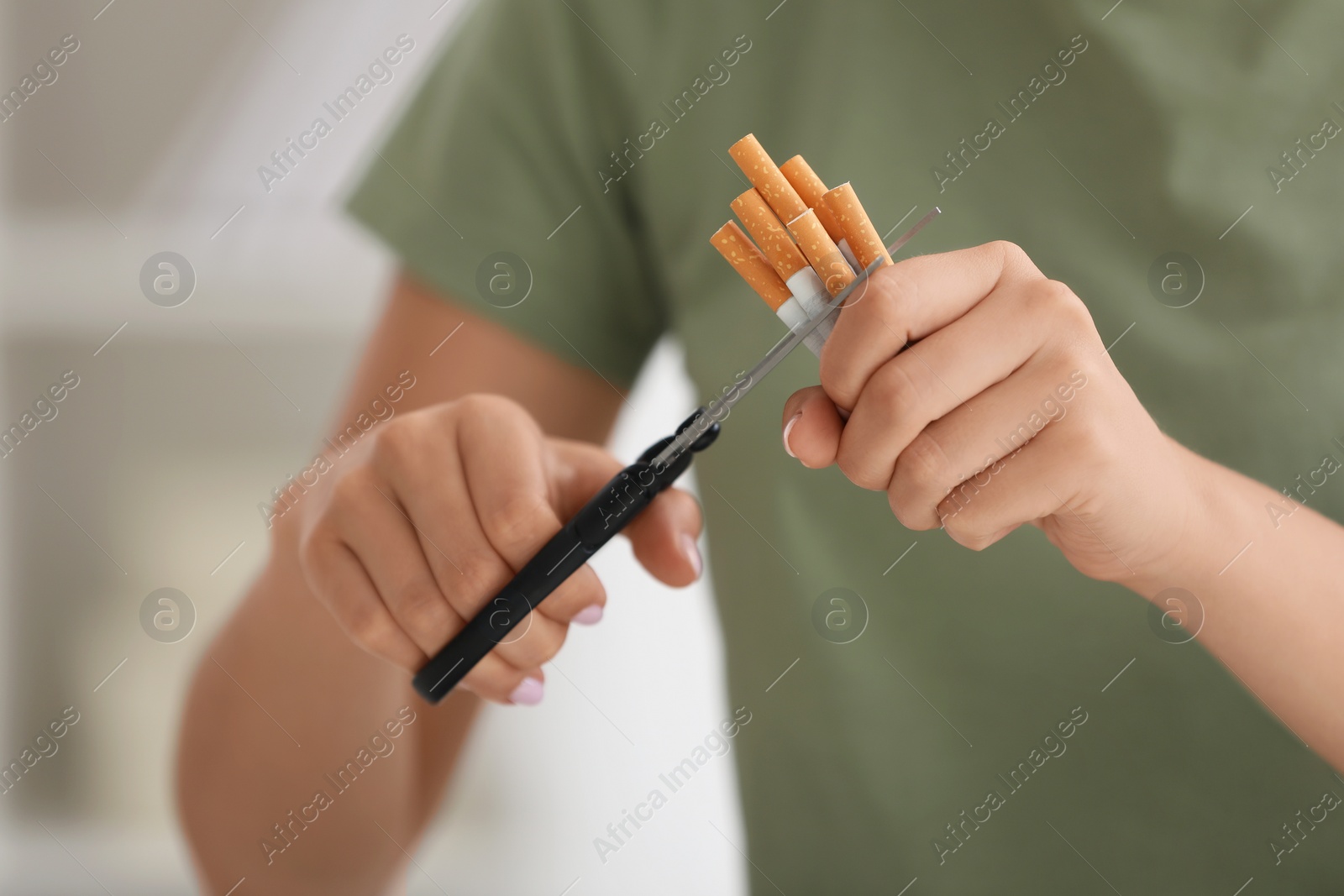 Photo of Stop smoking concept. Woman cutting cigarettes on light background, closeup