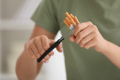 Photo of Stop smoking concept. Woman cutting cigarettes on light background, closeup