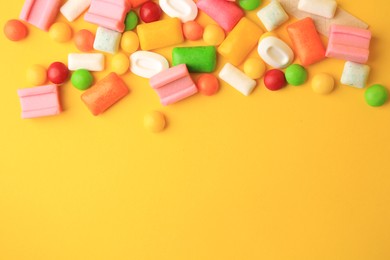 Photo of Many different chewing gums on yellow background, flat lay. Space for text