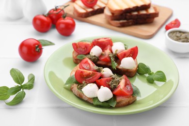 Photo of Delicious Caprese sandwiches with mozzarella, tomatoes, basil and pesto sauce on white tiled table