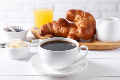 Photo of Fresh croissants, butter and coffee on white wooden table. Tasty breakfast