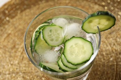 Photo of Glass of fresh cucumber water on golden background, closeup
