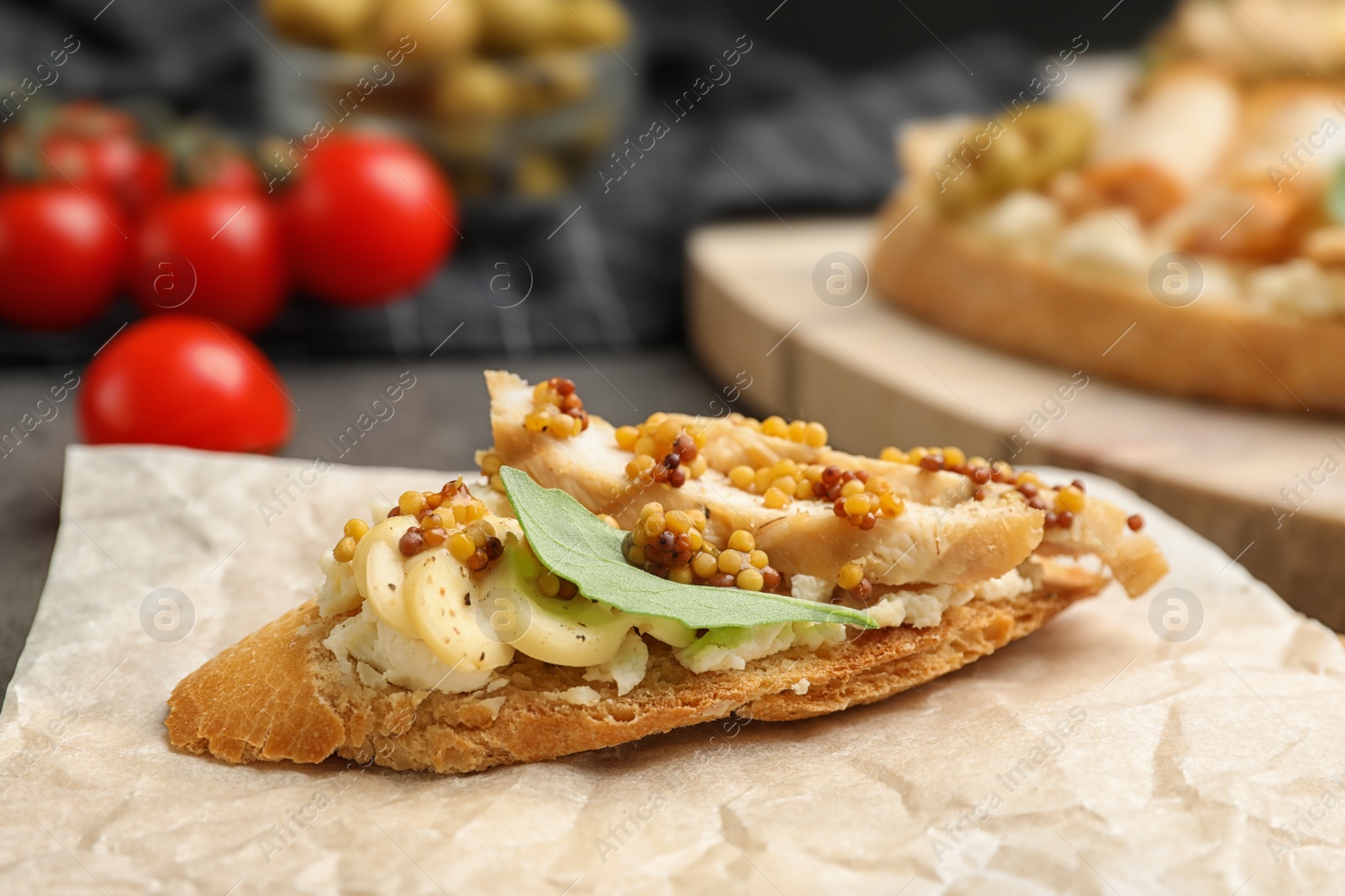 Photo of Parchment with delicious chicken bruschetta on table, closeup