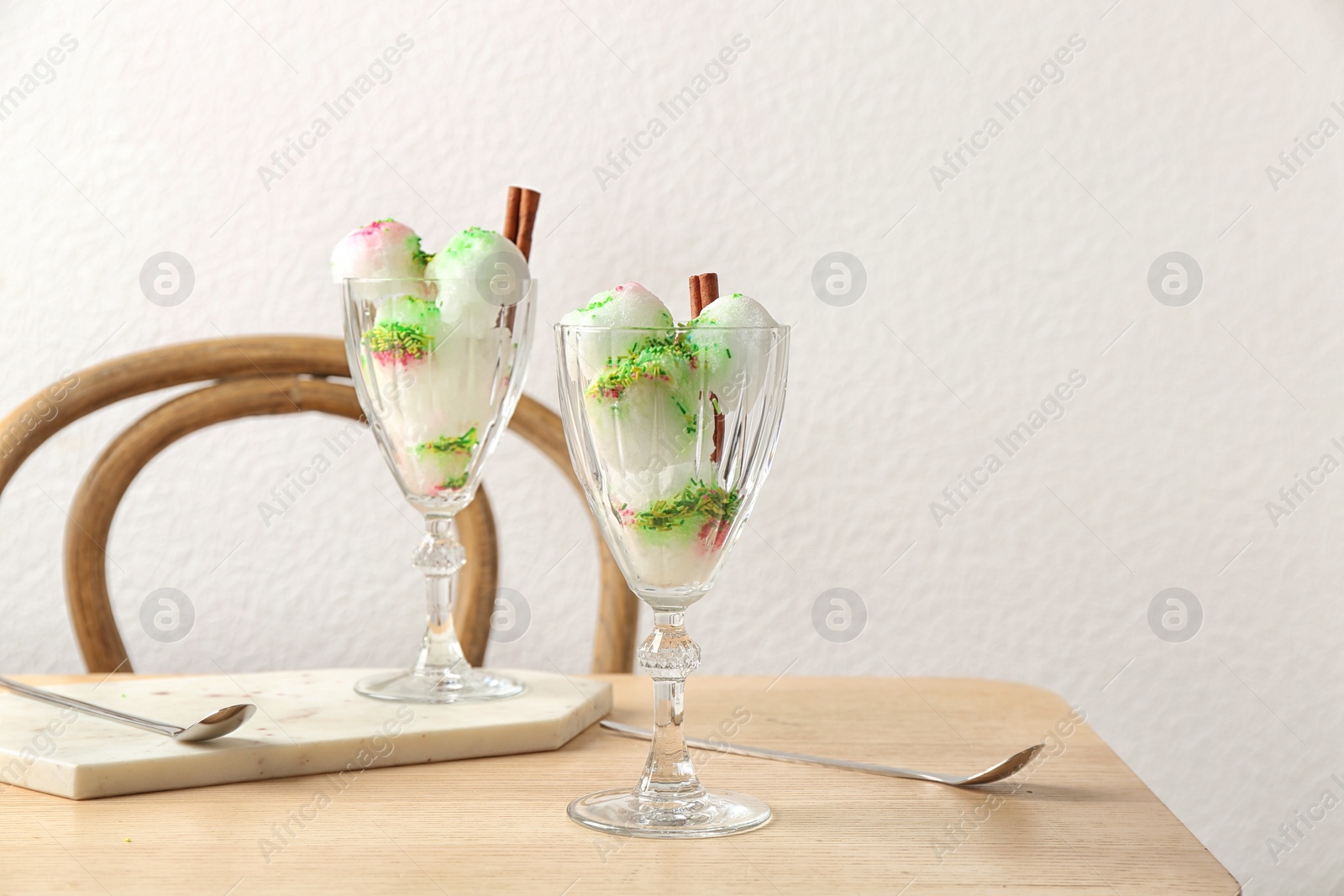 Photo of Glasses with snow ice cream dessert on table against light wall. Space for text