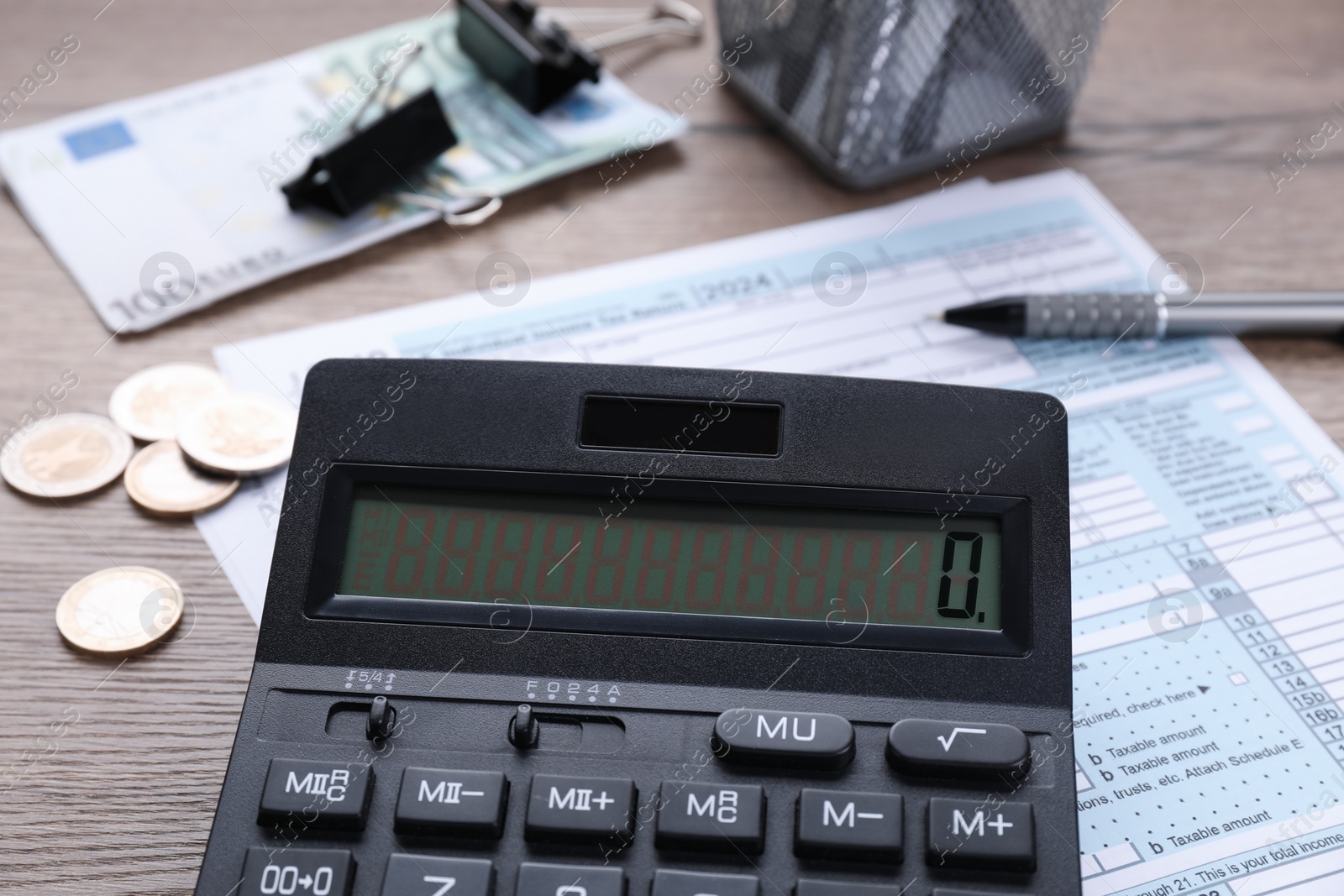 Photo of Tax accounting. Calculator, document, money and stationery on wooden table, closeup