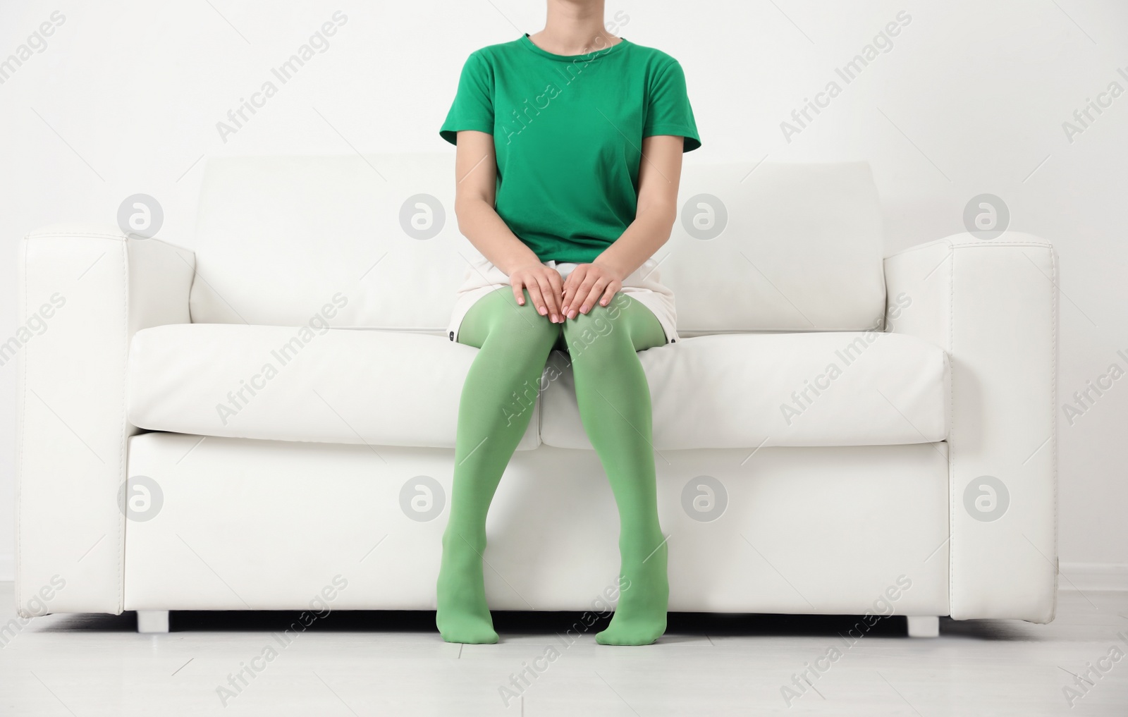 Photo of Woman wearing green tights sitting on sofa indoors, closeup