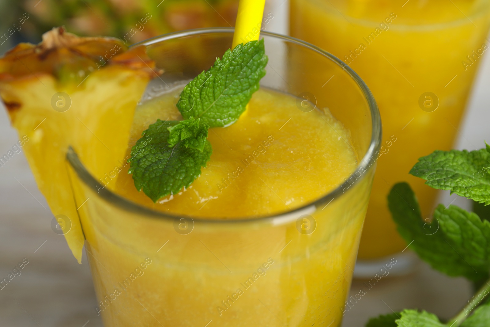 Photo of Glass of tasty pineapple smoothie and mint on table, closeup