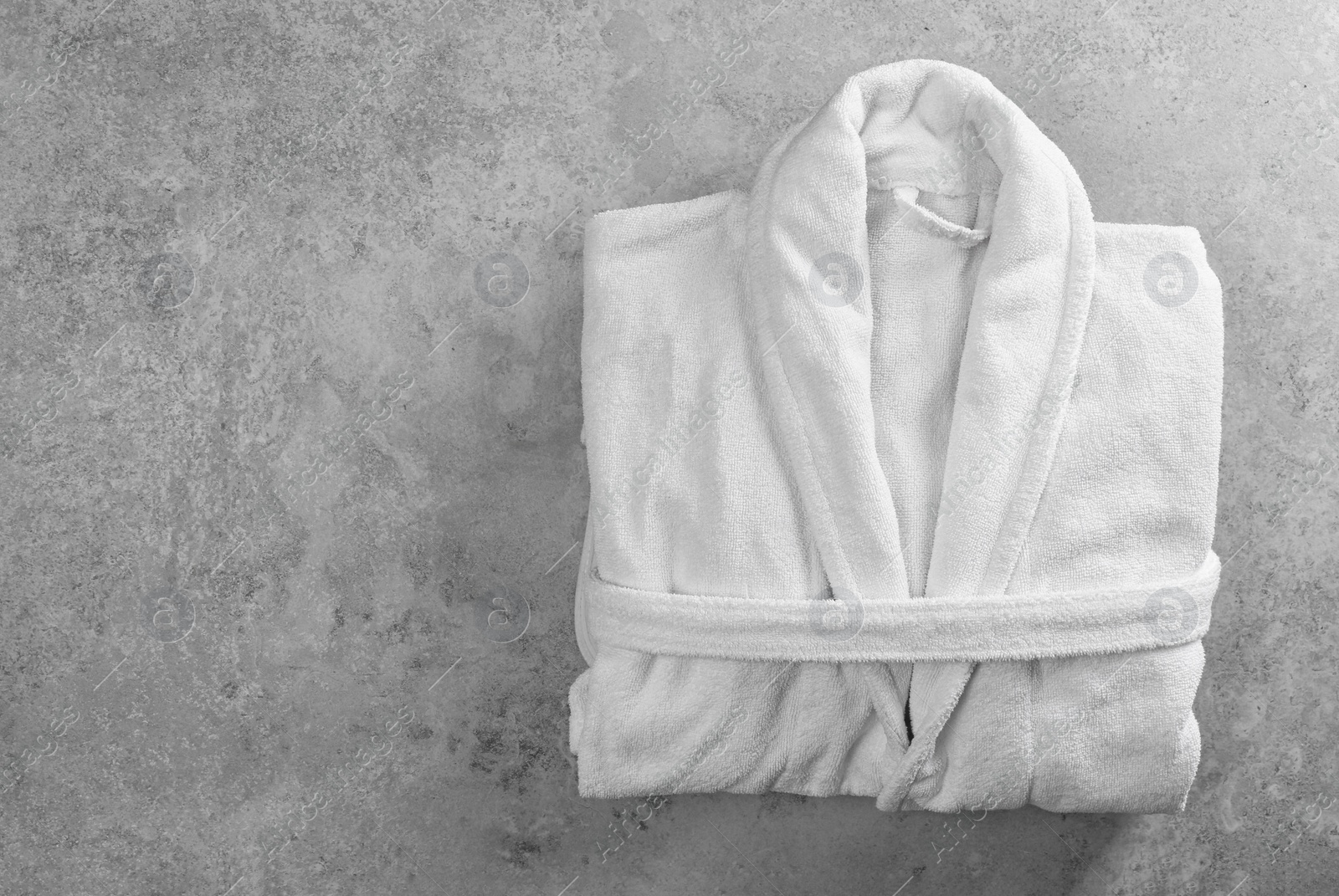 Photo of Clean folded bathrobe on grey stone background, top view. Space for text