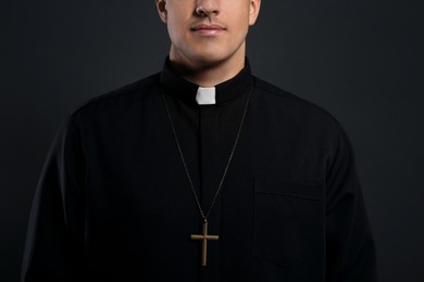 Photo of Priest with cross on black background, closeup
