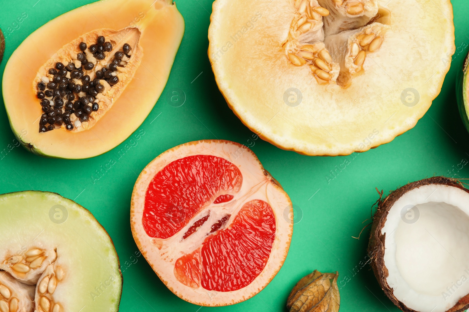 Photo of Flat lay composition with tasty melon and fresh tropical fruits on green background