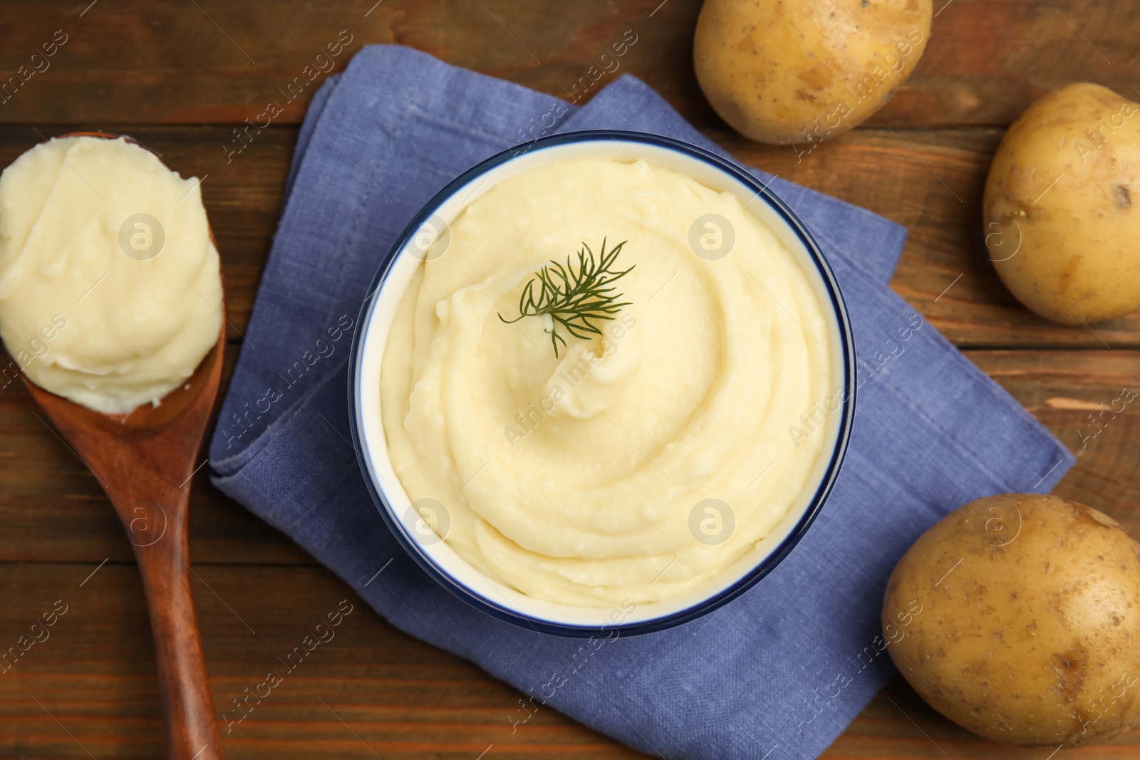 Photo of Freshly cooked homemade mashed potatoes, spoon and raw vegetables on wooden table, flat lay