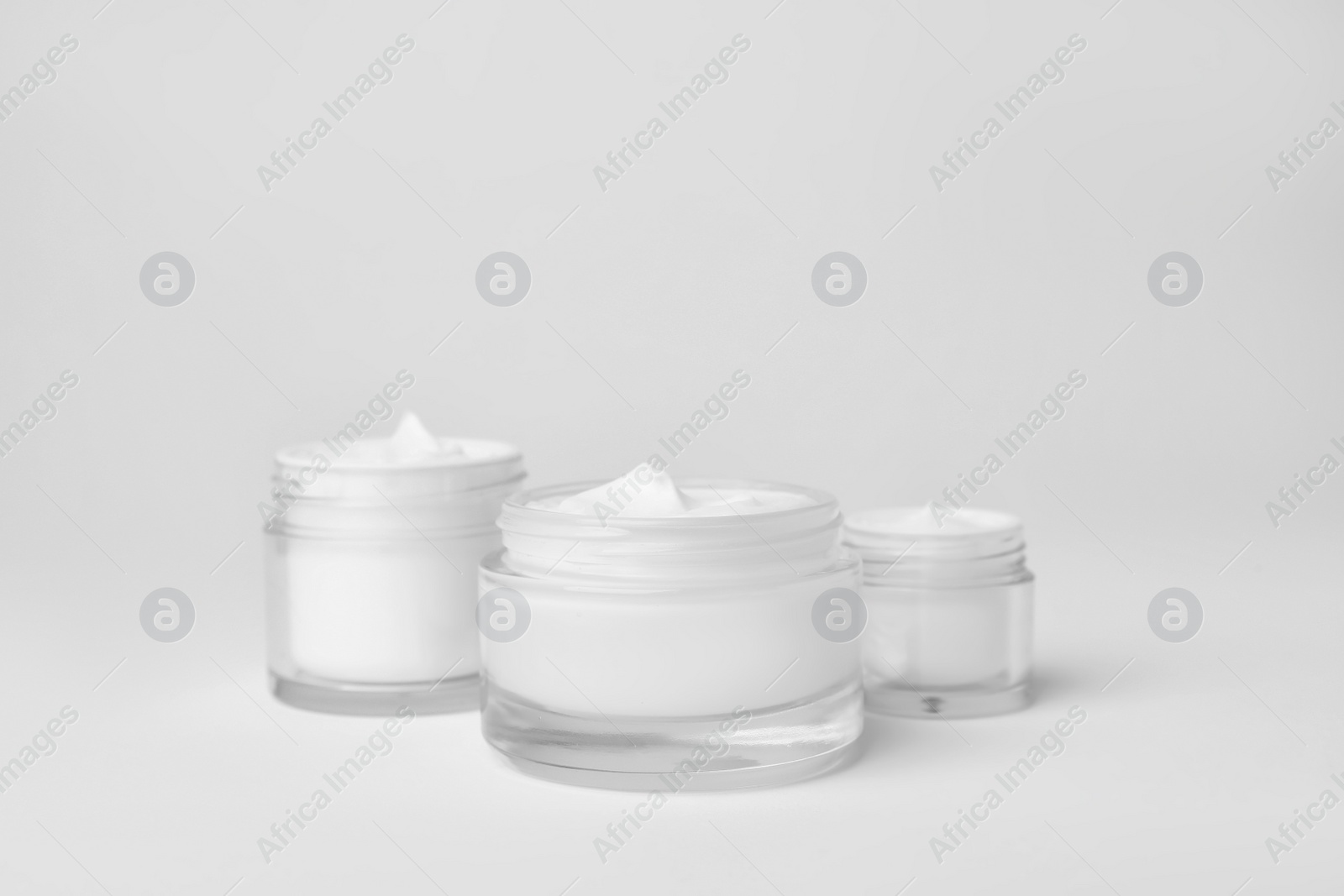 Photo of Jars of cosmetic products on light background