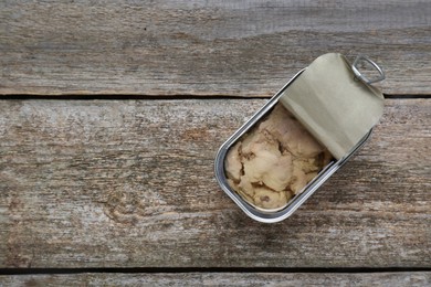 Photo of Open tin can of tasty cod liver on wooden table, top view. Space for text