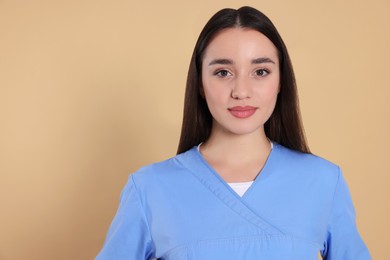 Photo of Portrait of nurse in medical uniform on light brown background, space for text