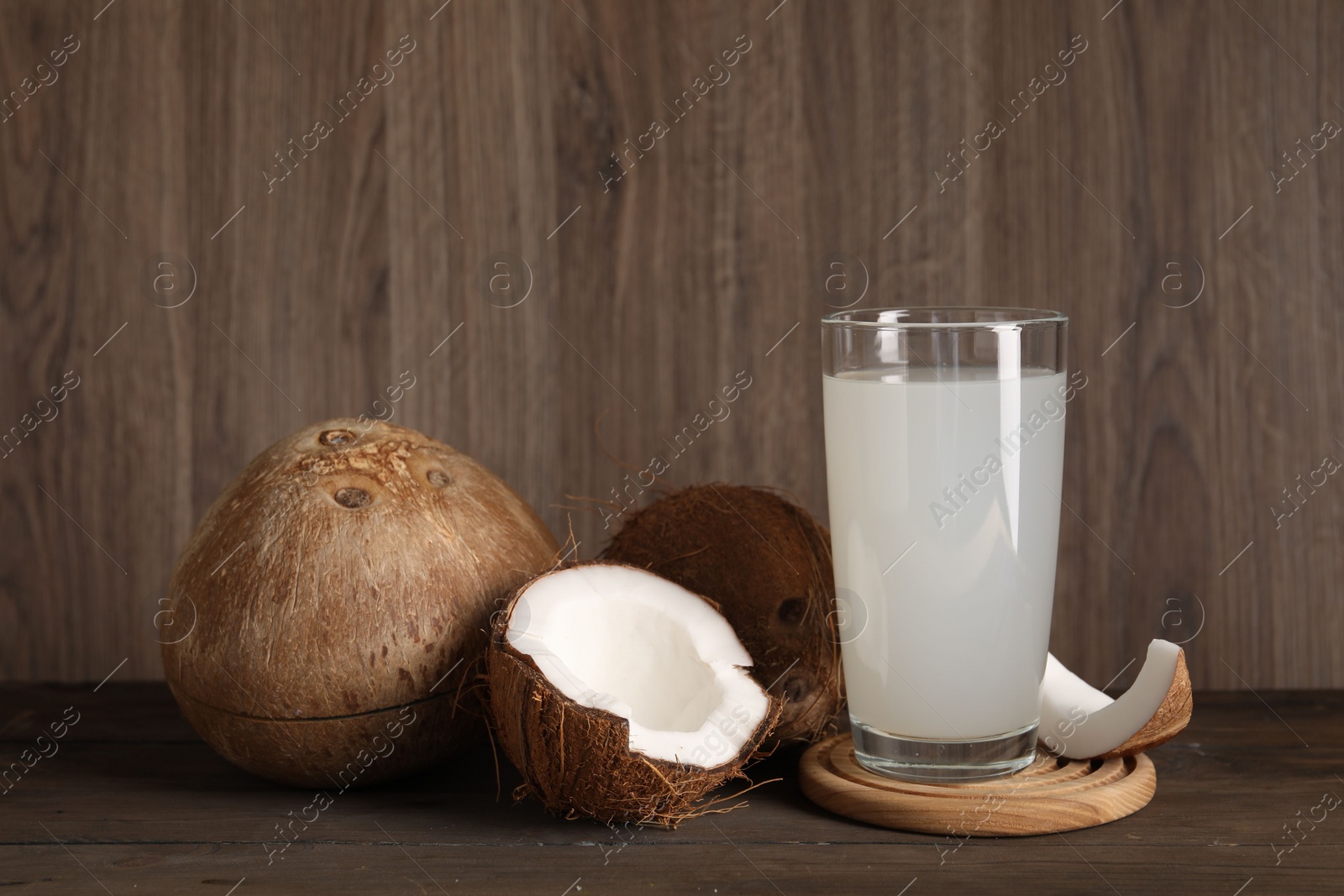 Photo of Glass of coconut water and nuts on wooden table