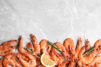 Photo of Delicious cooked shrimps with rosemary and lemon on grey marble table, flat lay. Space for text