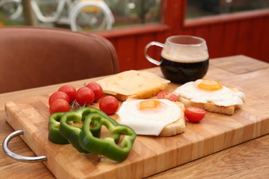 Tasty toasts with fried eggs, cheese and vegetables on wooden table indoors