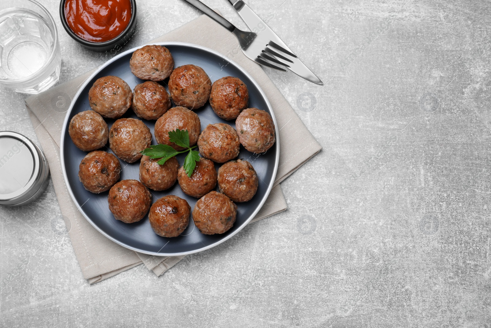 Photo of Tasty cooked meatballs with parsley served on light grey table, flat lay, Space for text