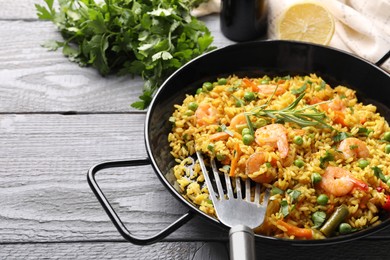 Photo of Tasty rice with shrimps and vegetables served on grey wooden table. Space for text